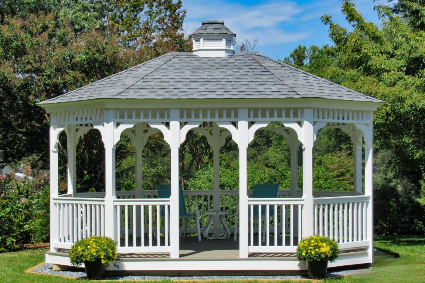 Front View of 12x16 Vinyl Oval Gazebo with plants and in front of trees
