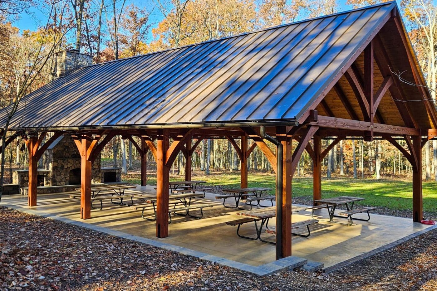 30x50 Kingston Pro Timber frame pavilion over patio with picnic benches in fall forest