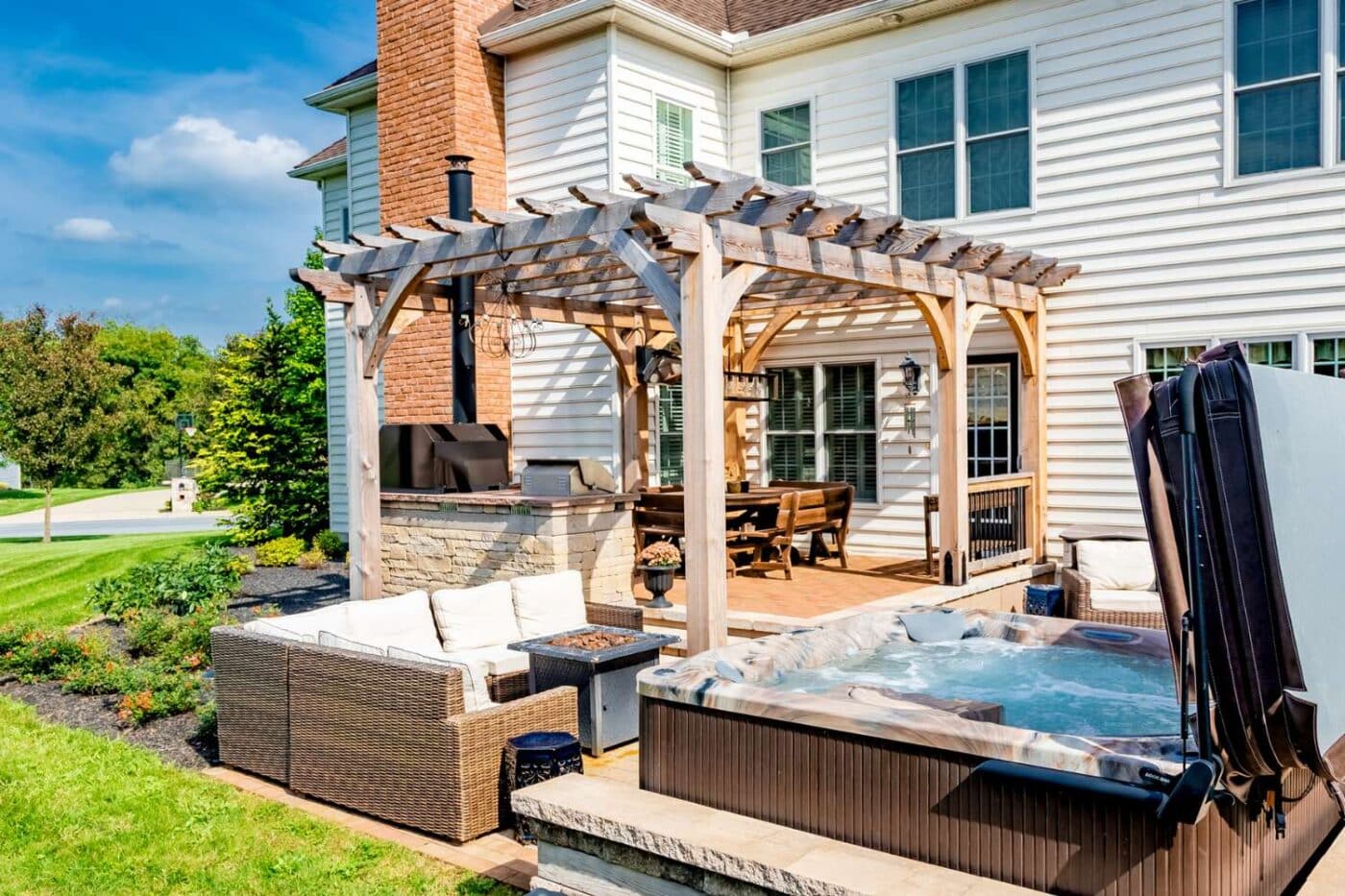 Boulder wooden pergola outside home, besides hot tub, and over grill