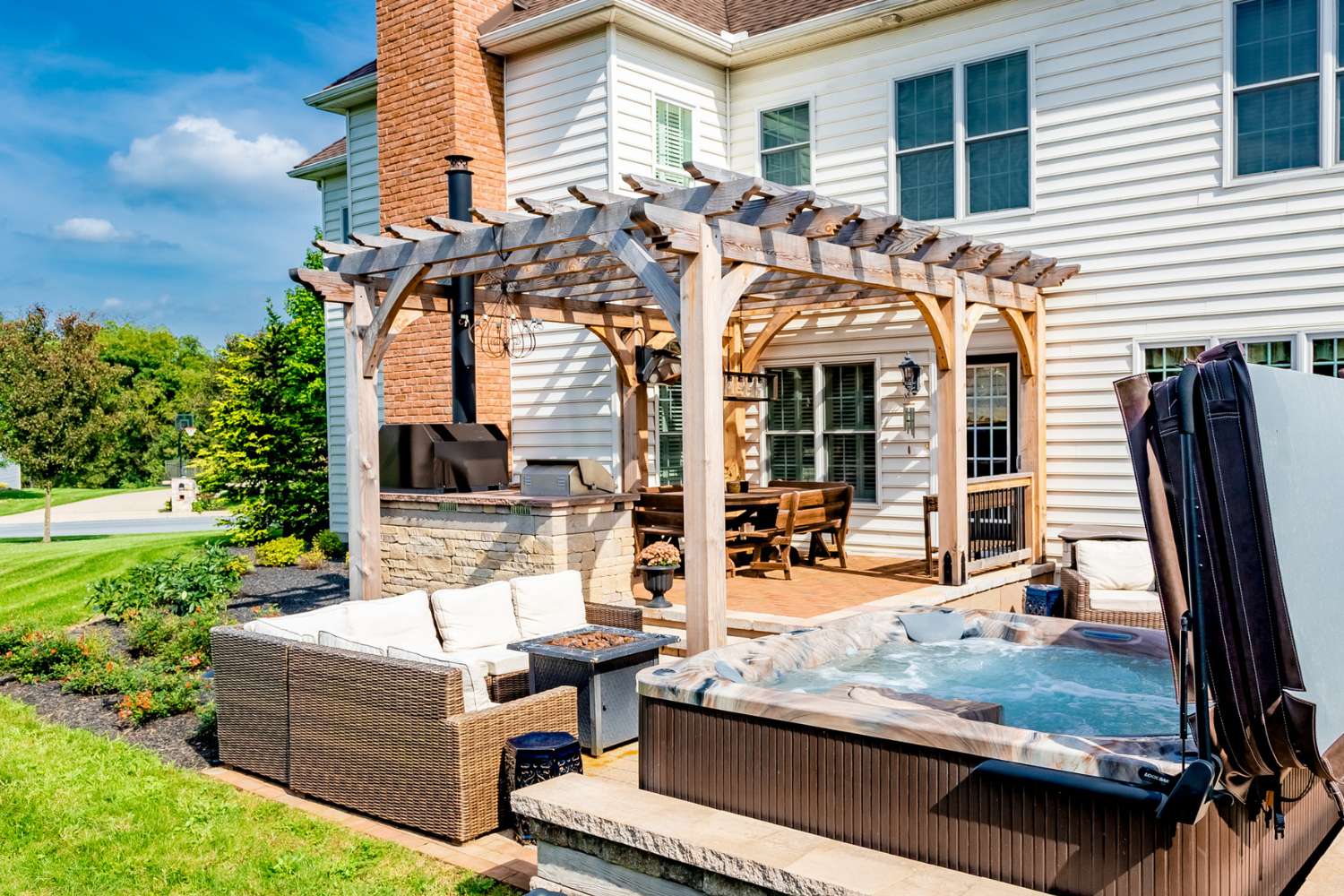 Boulder wooden pergola outside home, besides hot tub, and over grill
