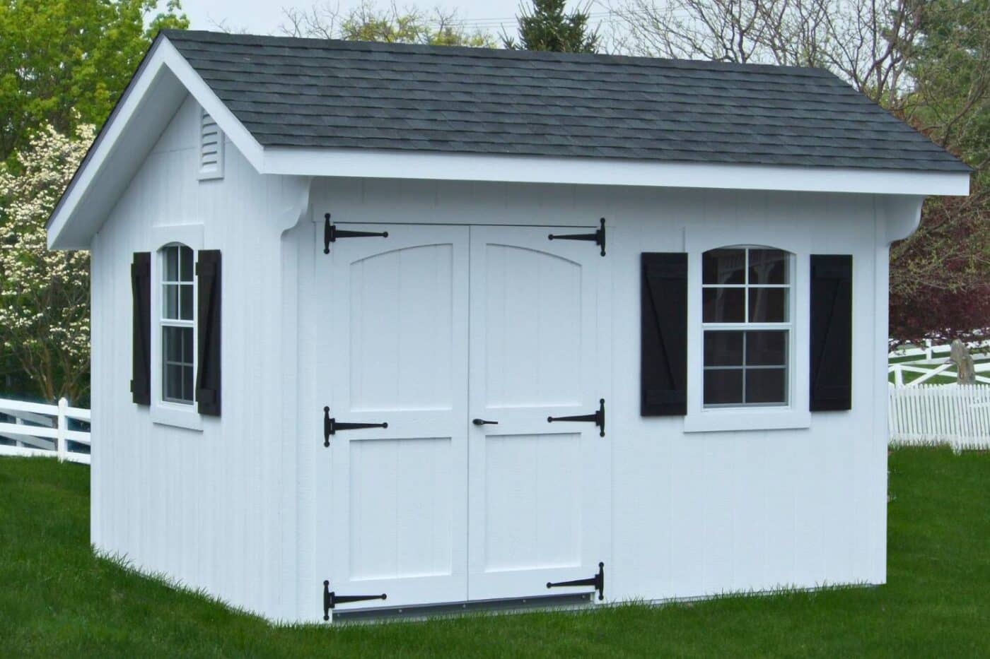 White wood designer carriage shed on green grass with black shutters