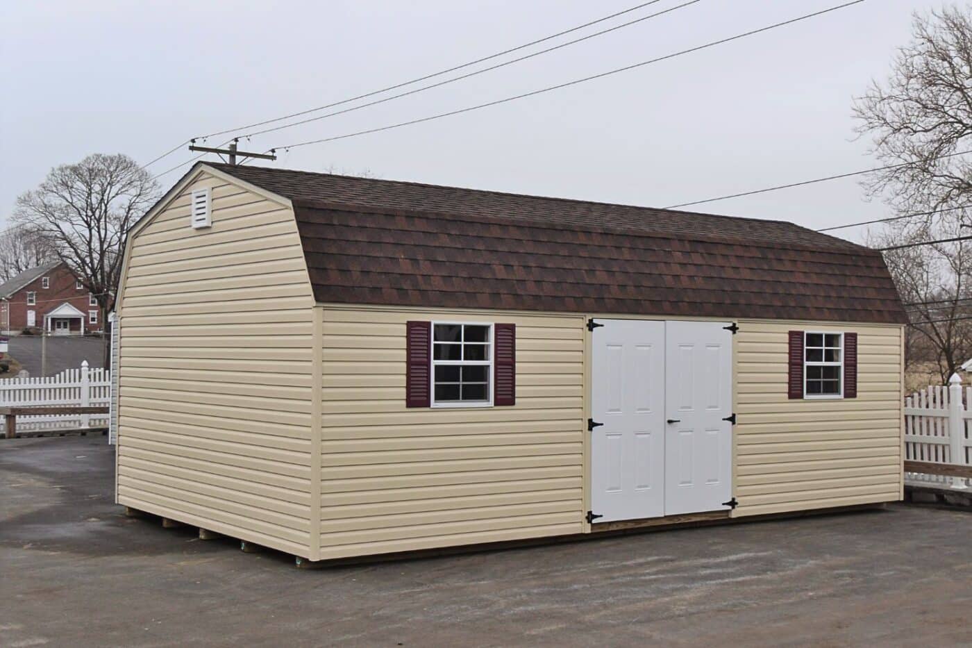 The Designer High Barn Shed 5 Vinyl high barn shed on concrete lot with white doors and beige siding