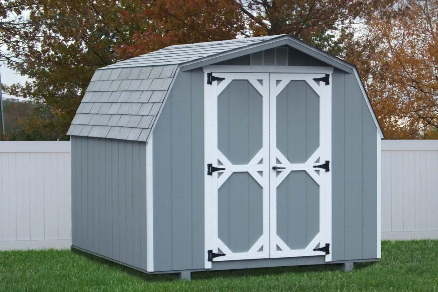 The Mini Barn Shed 2 Mini Barn Shed with wood exterior and white trim by white picket fence
