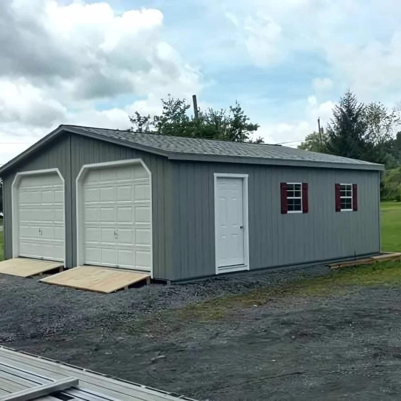 The Modular Garage 2 Gray two car modular garages with white doors and trim, red shutters, and asphalt shingle roofs