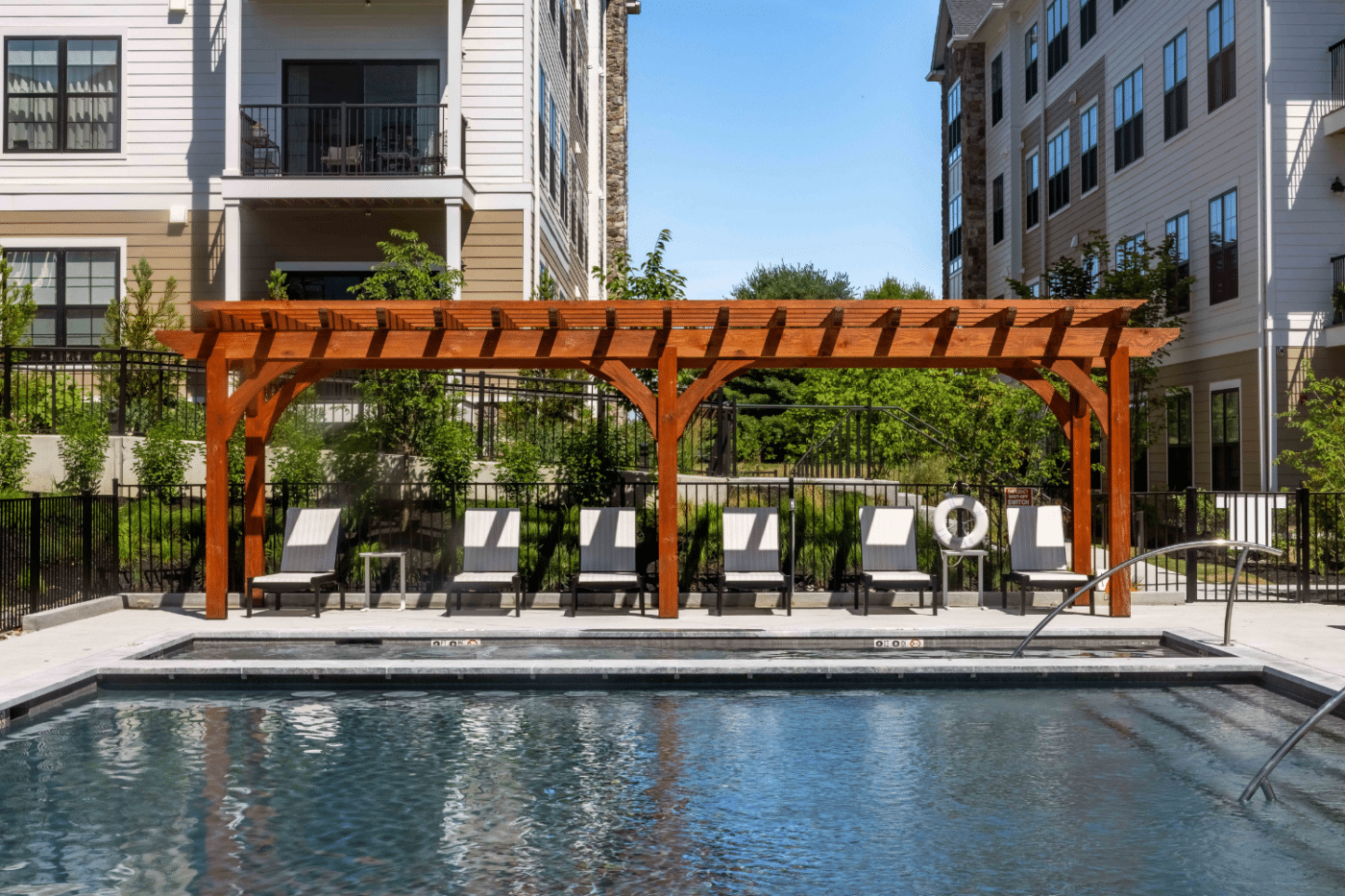 View of 7x30 pergola across the pool with seating underneath