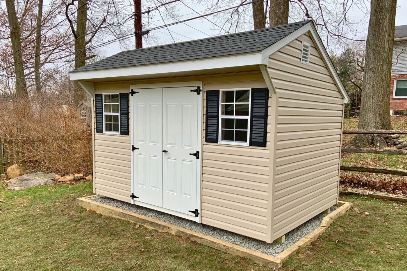 Beige carriage shed with white double doors and black shutters