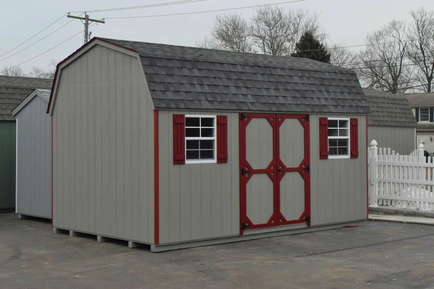 The Standard High Barn Shed 4 Gray and red wood standard high barn shed on concrete lot