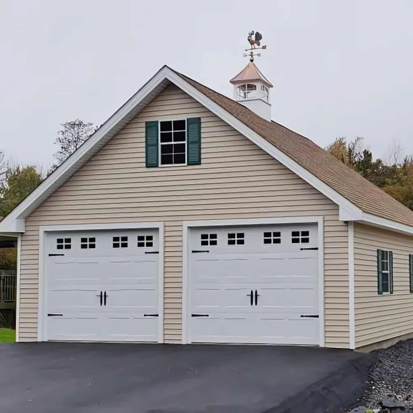 The A-Frame Truss Garage 3 Beige siding with white garage doors, green windows shutters and a cupola