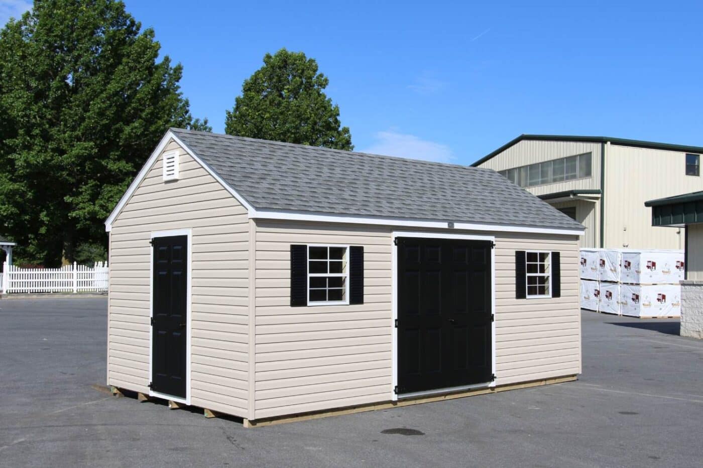 The Designer Workshop Shed 5 Standard Workshop with vinyl exterior in concrete lot with dark doors and window shutters