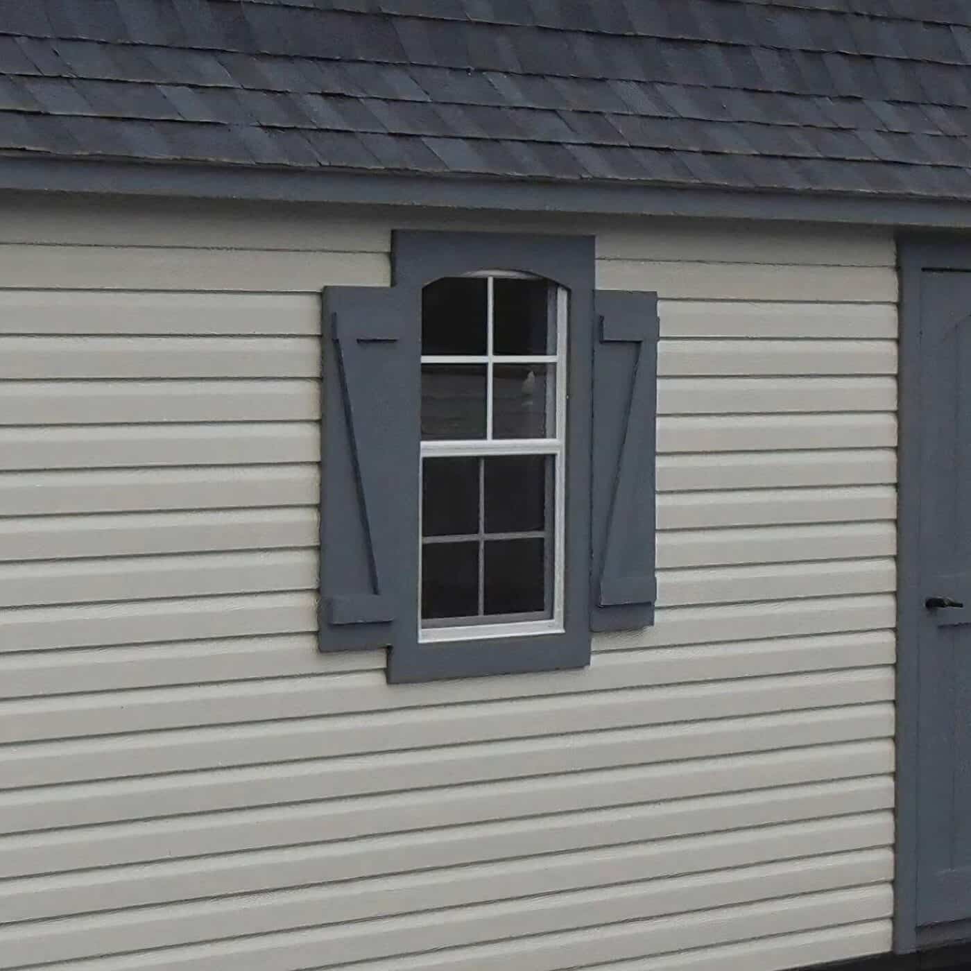 The Designer High Barn Garage 6 Beige shed with close up of window with dark gray picture frame and shutters