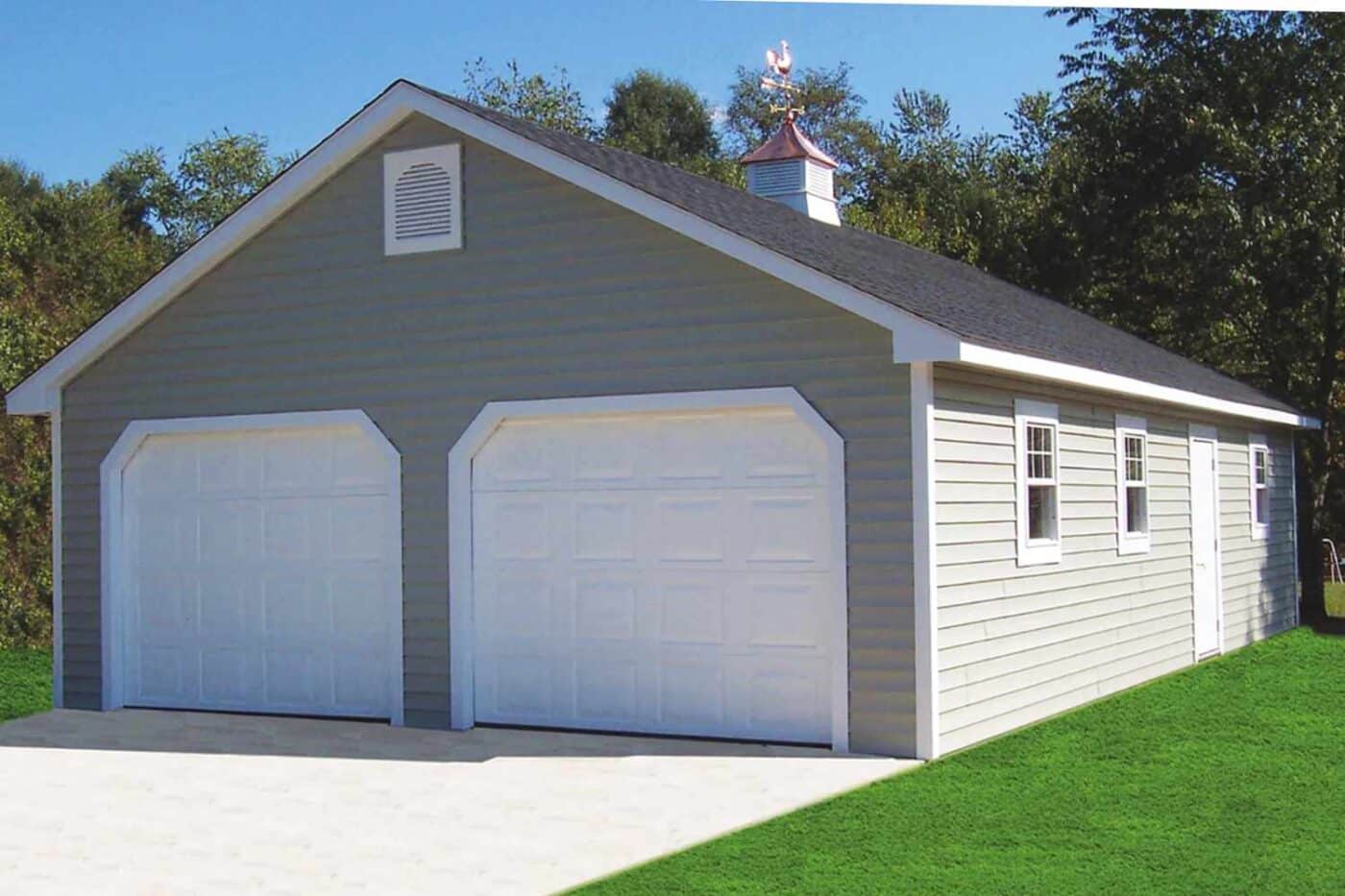 Truss Garage with white garage doors, trim, and cupola