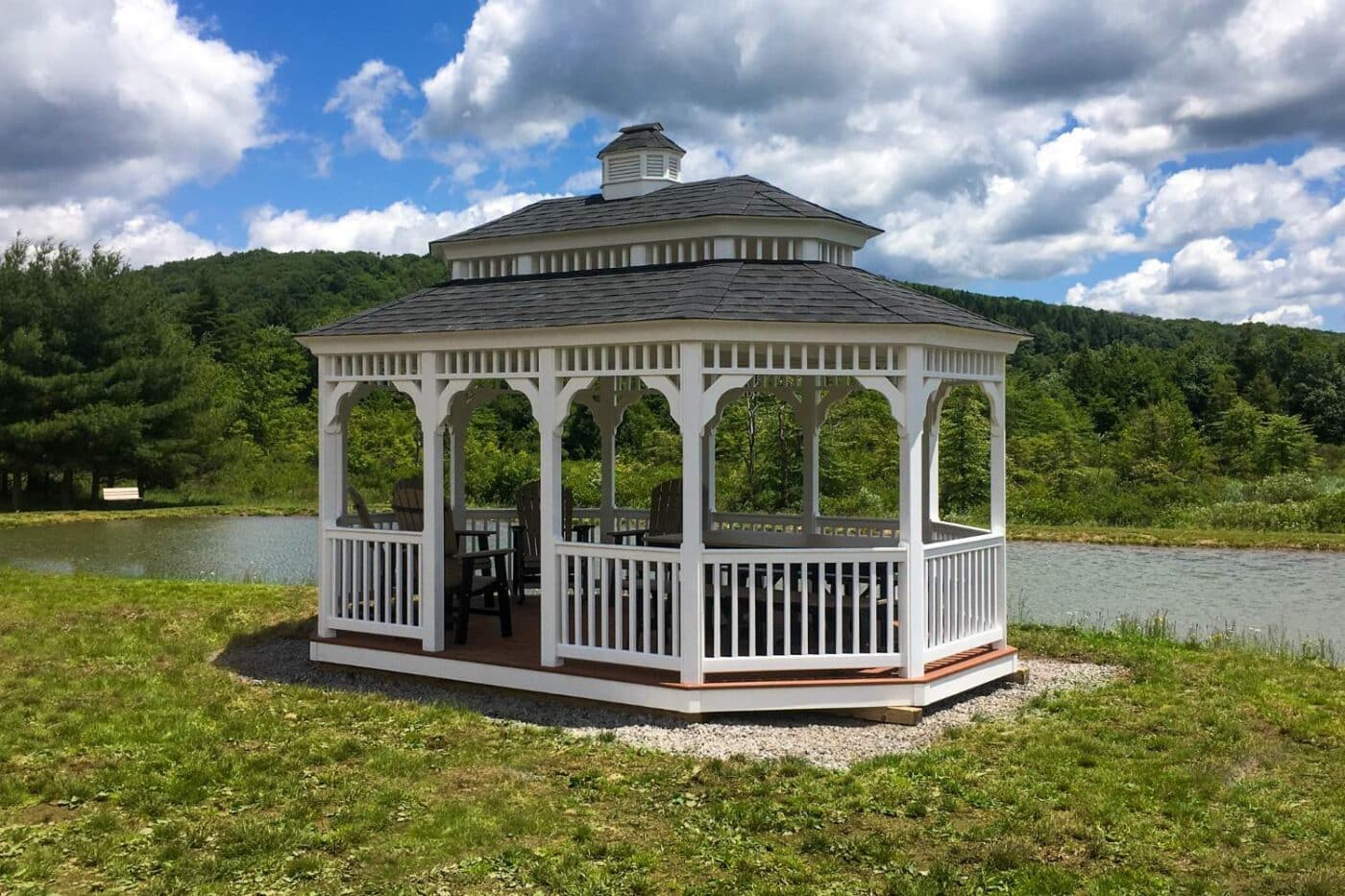Vinyl Oval gazebo with seating underneath in front of lake on gravel pad