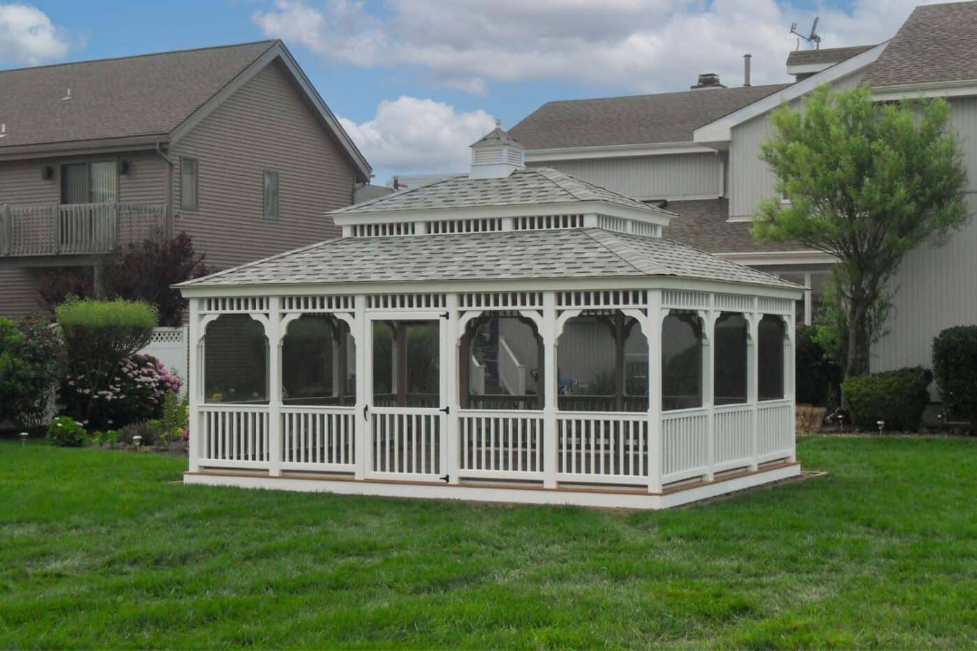 Vinyl Rectangle Gazebo outside home with double roof, cupola, and screened in windows