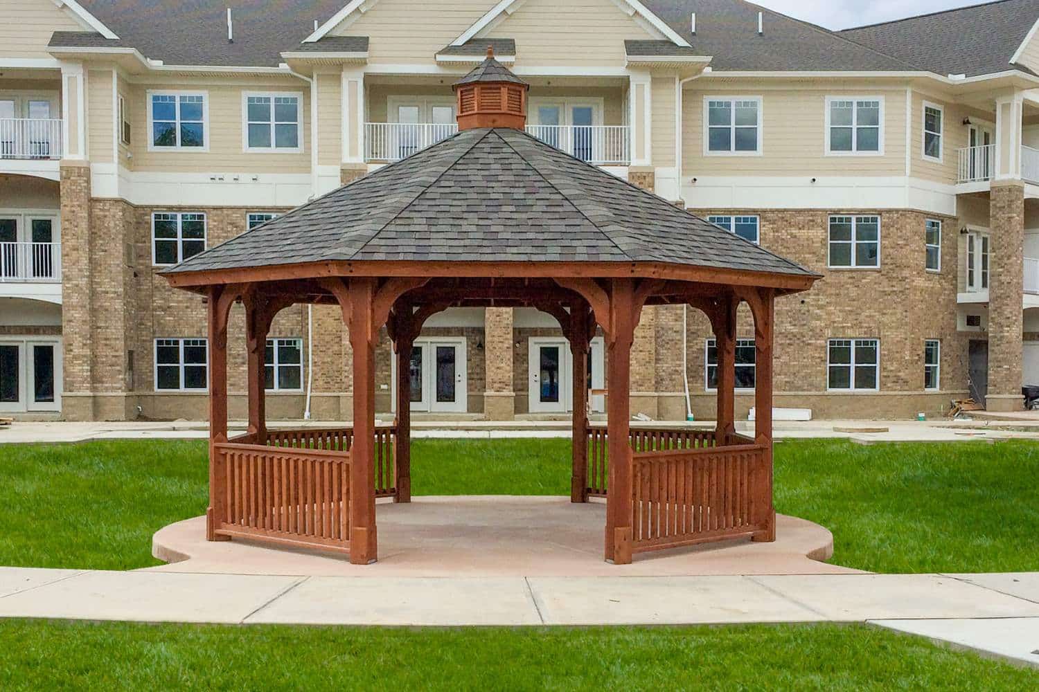 Wood Octagon Gazebo on concrete foundation in front of apartment building