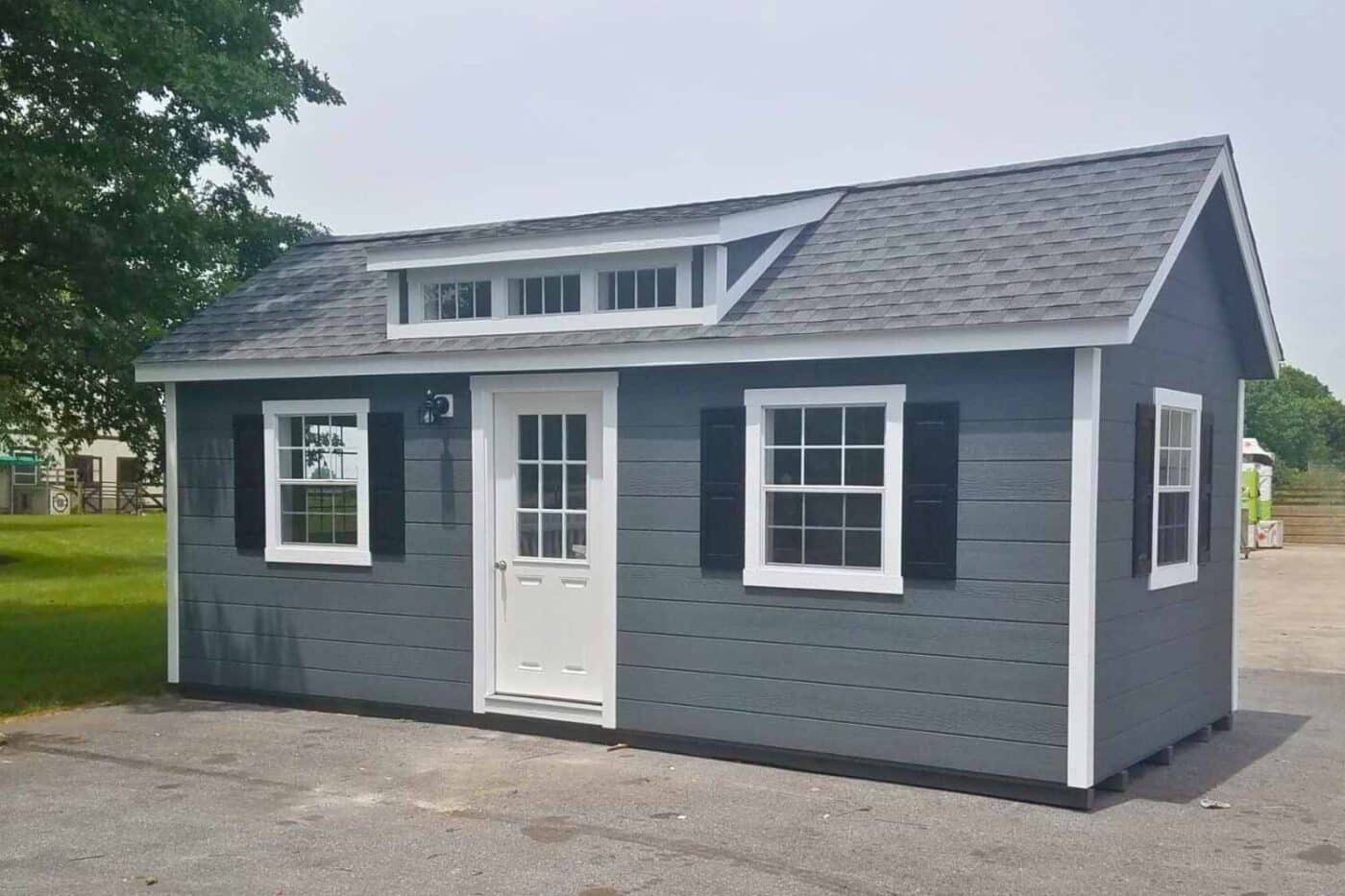 Gray Workshop Shed with white door, windows, and trim. Windows on all sides with gray asphalt shingle roofing