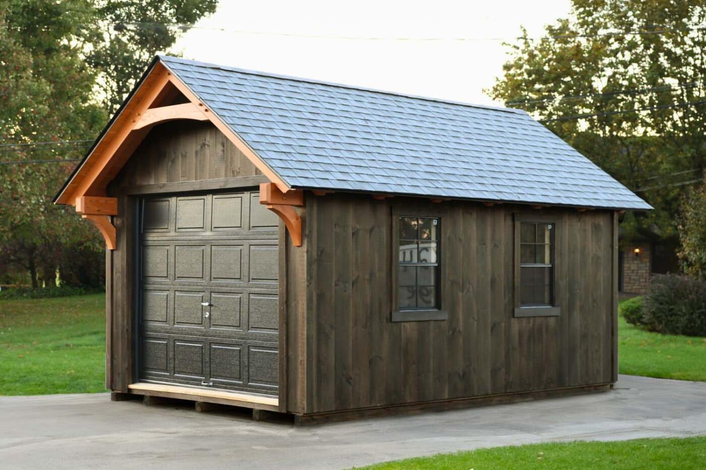 The York Timber Frame Shed on a driveway with garage door, two single windows and timber frame overhang