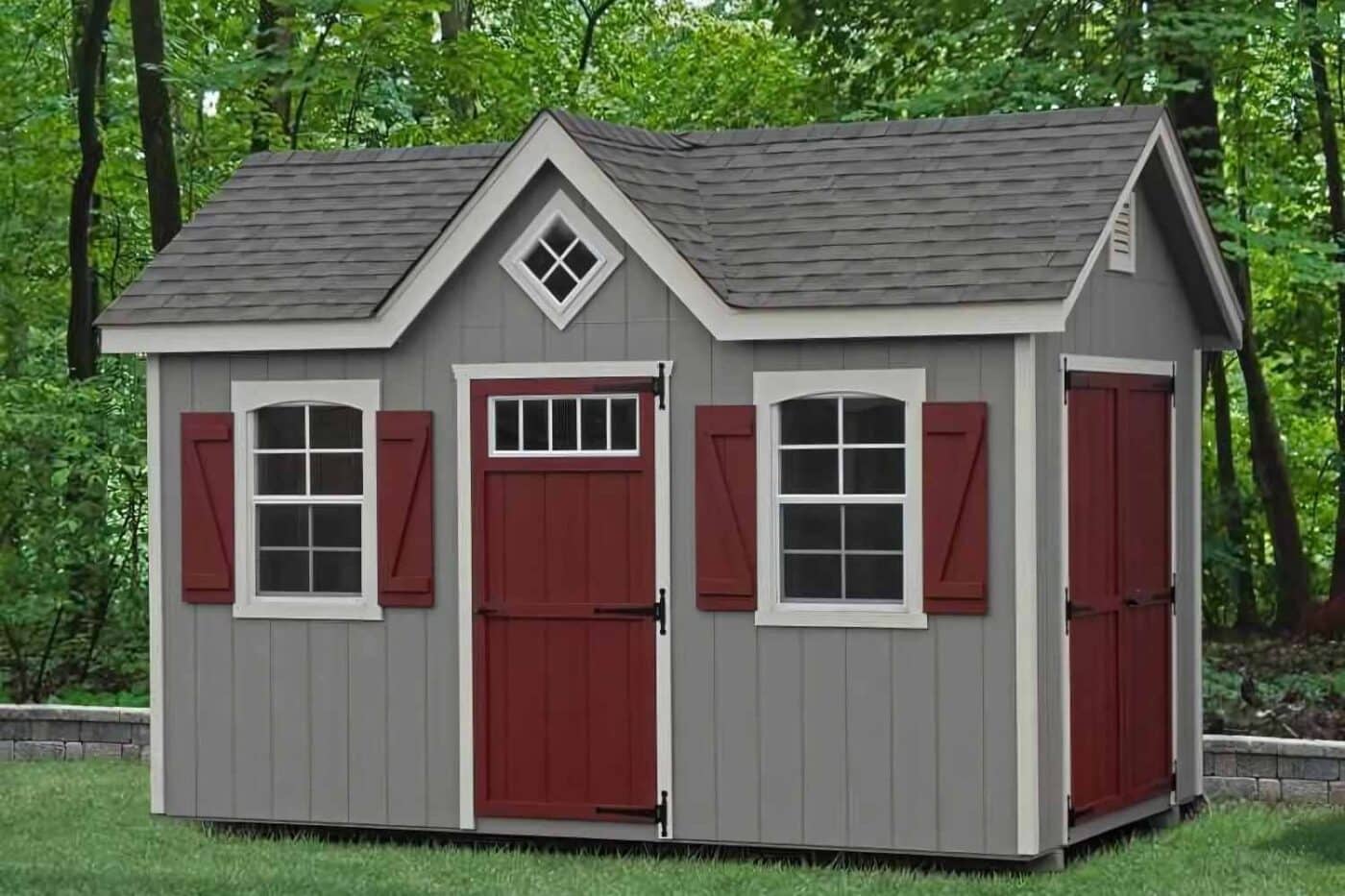 Gray and red cape cod shed in yard with trees