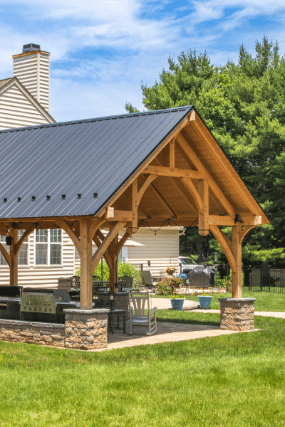 denali timber frame pavilion over seating area and grill with stone posts