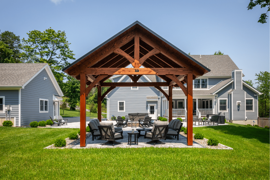 timber frame pavilion with black metal roof and seating area on concrete patio